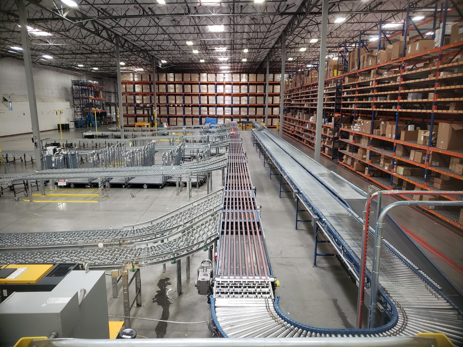 Warehouse conveyor installation alongside high-bay pallet racking